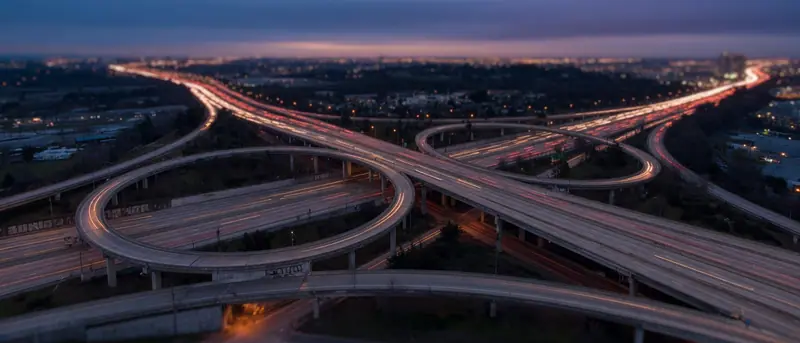 Illustration: a multi-level highway interchange at dusk.