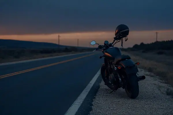 Illustration: a motorcycle on an open road at dusk.
