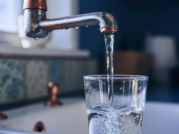 Illustration: water running from a tap into a glass.